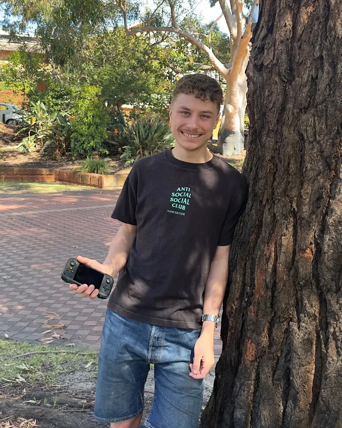 Ankiboy founder Austin standing beside a tree and holding the handheld